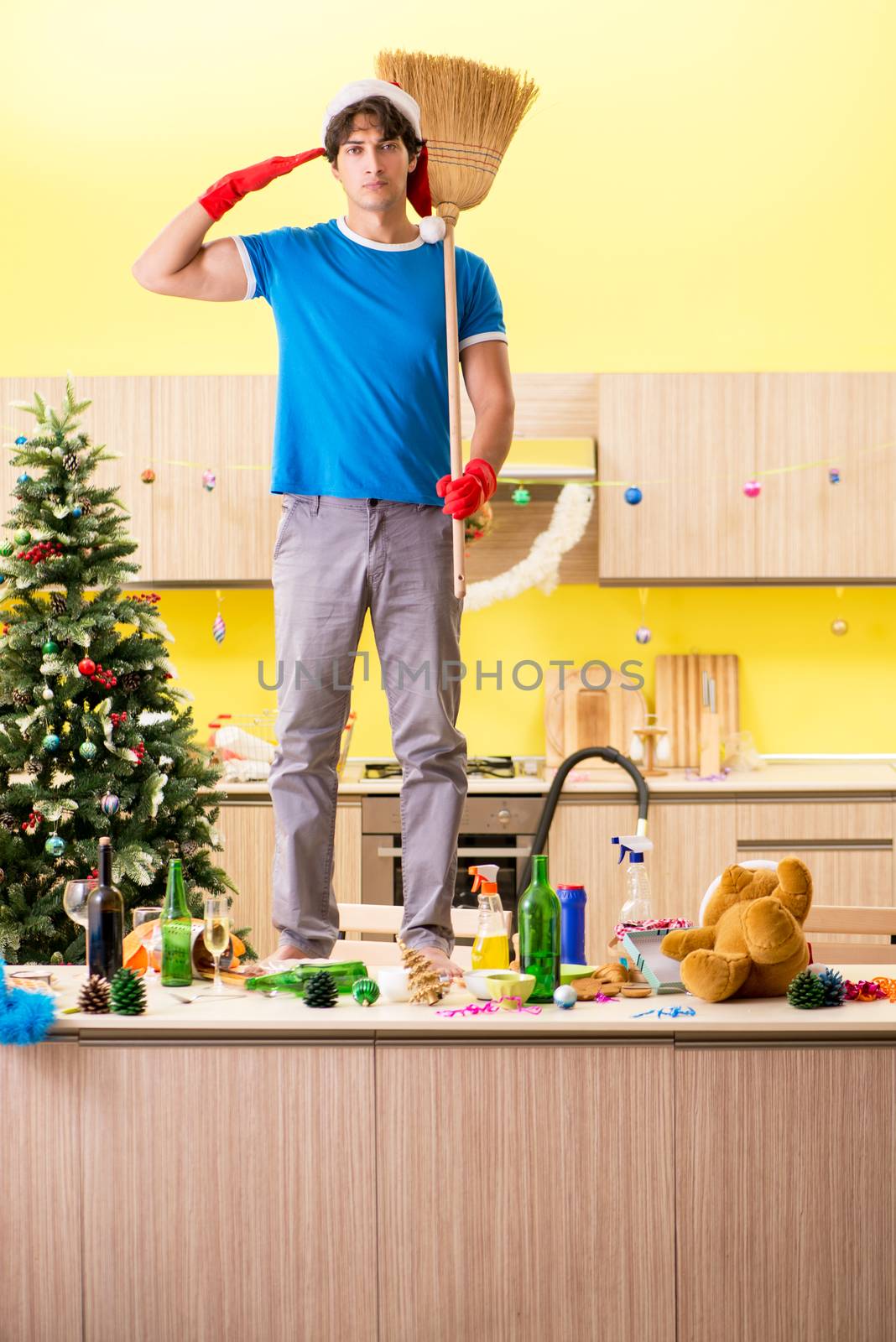 Young man cleaning kitchen after Christmas party 