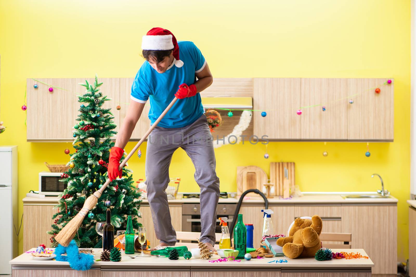 Young man cleaning kitchen after Christmas party 