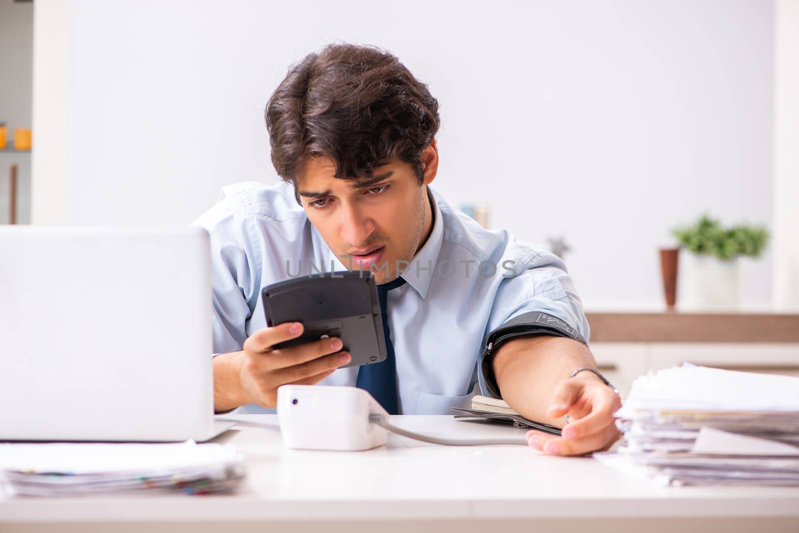 Man under stress measuring his blood pressure
