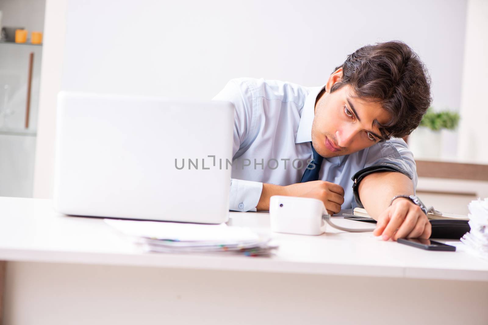 Man under stress measuring his blood pressure