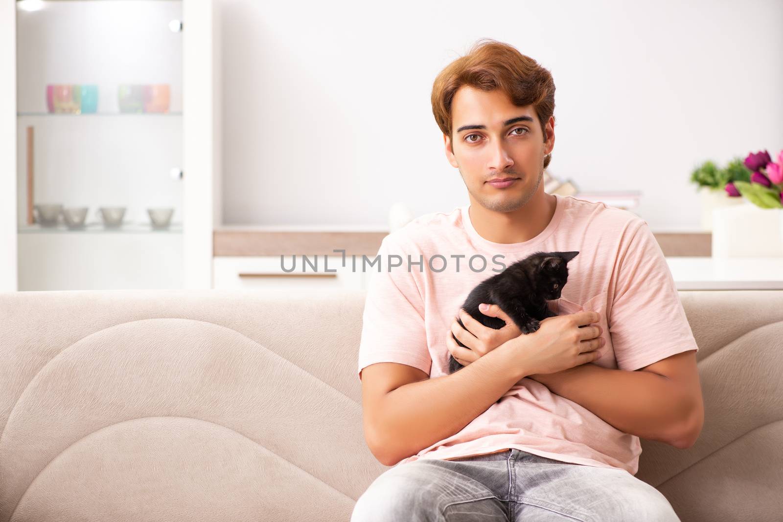 Young man playing with kitten at home