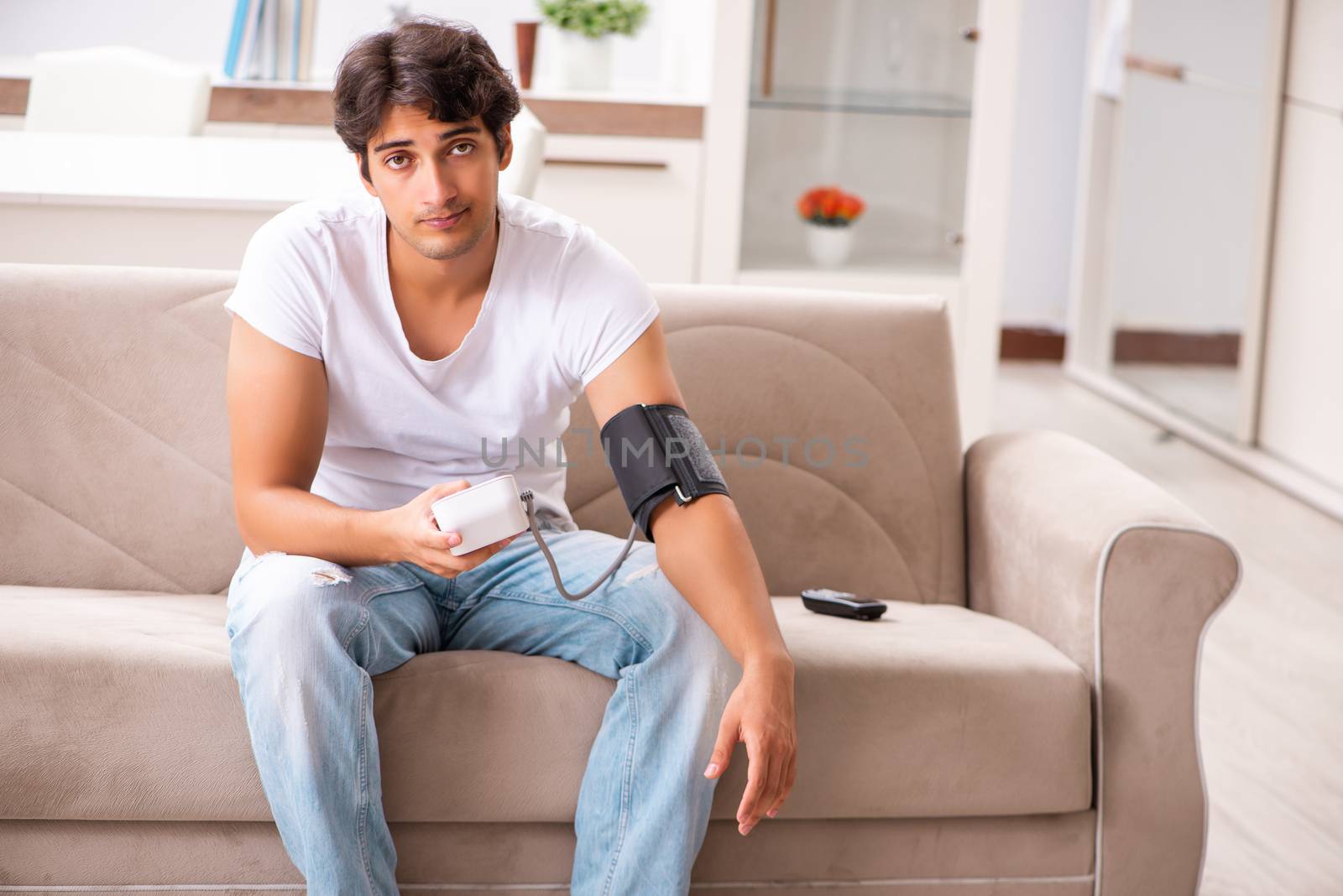 Young man measuring blood pressure at home