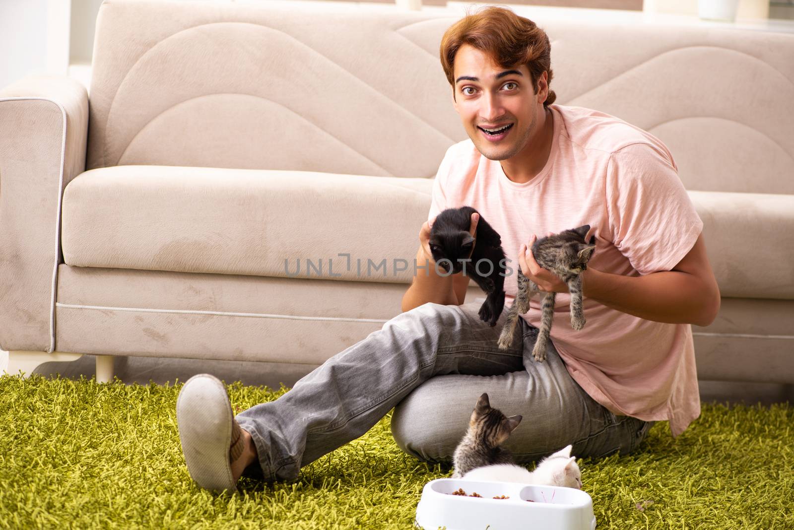 Young man playing with kitten at home