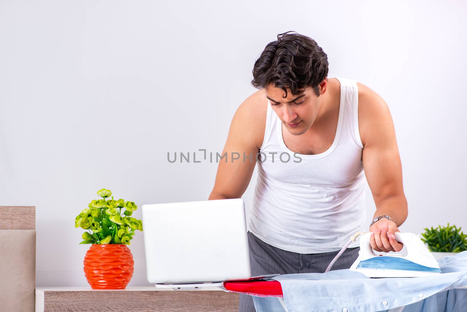 Young man freelancer ironing in the bedroom 