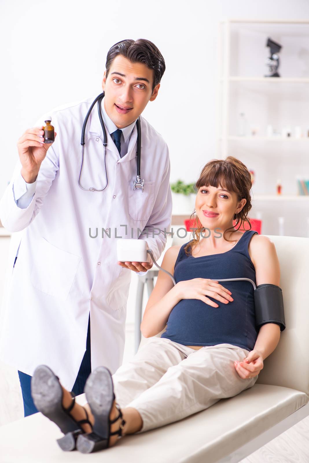 Young doctor checking pregnant woman's blood pressure