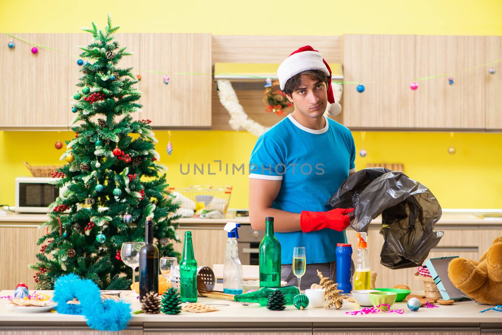 Young man cleaning kitchen after Christmas party 