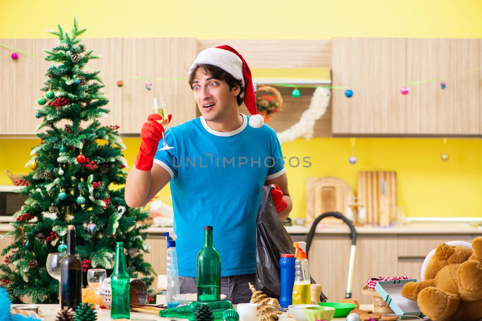 Young man cleaning kitchen after Christmas party 