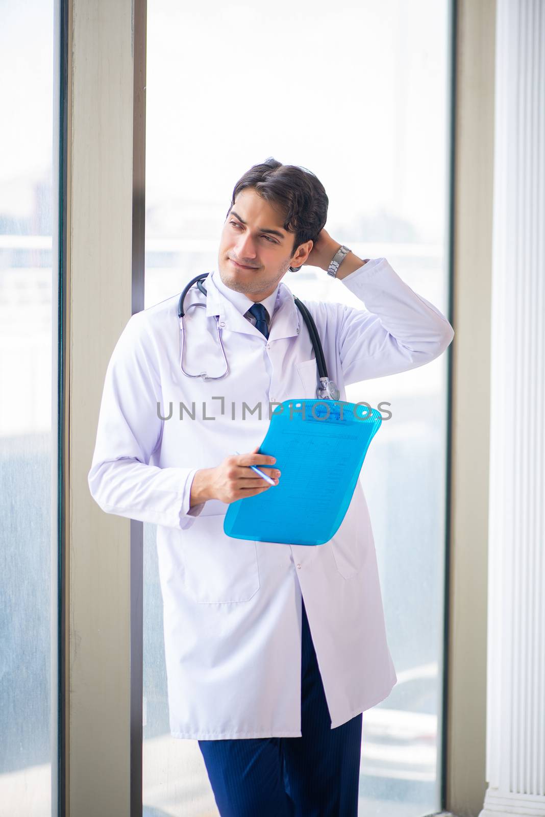 Young handsome doctor standing at the window 