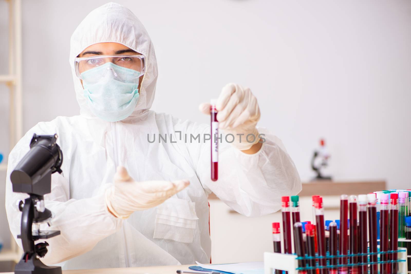 Young handsome lab assistant testing blood samples in hospital 