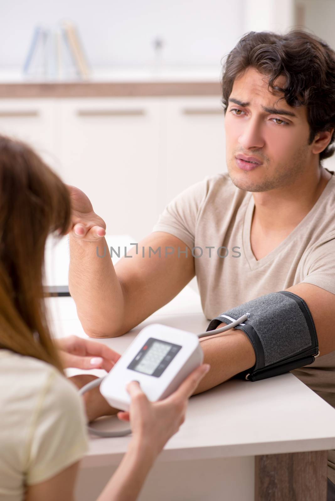 Wife checking husband's blood pressure  