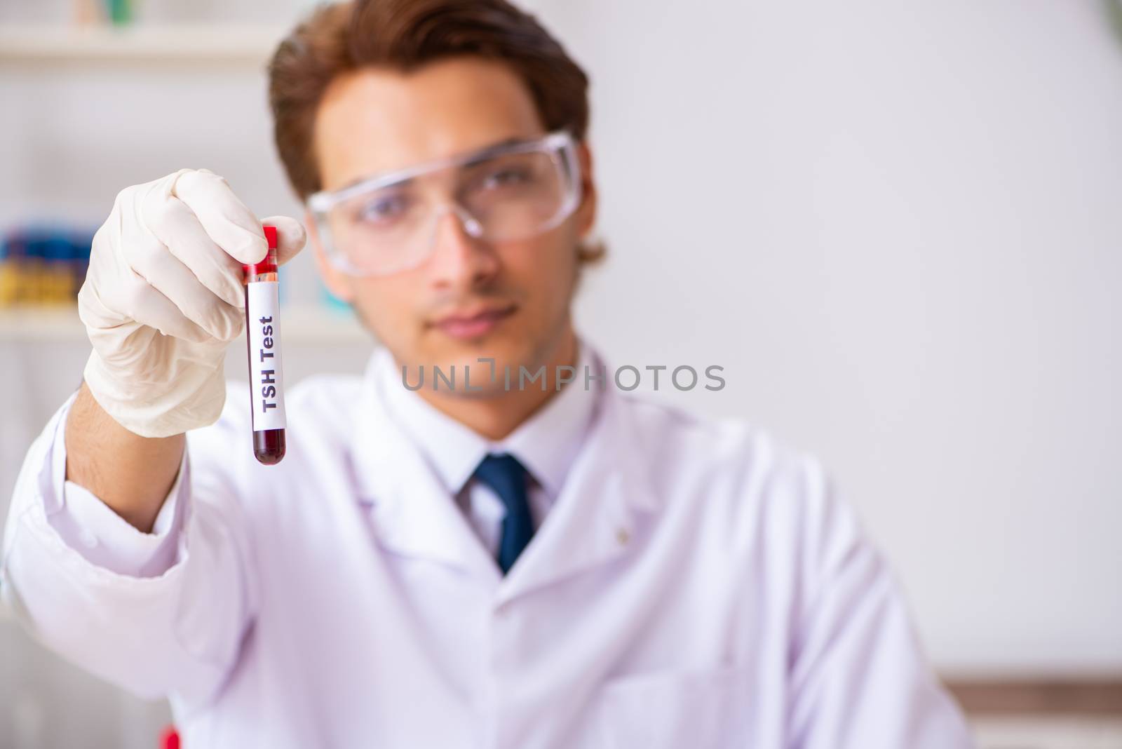 Young handsome lab assistant testing blood samples in hospital 