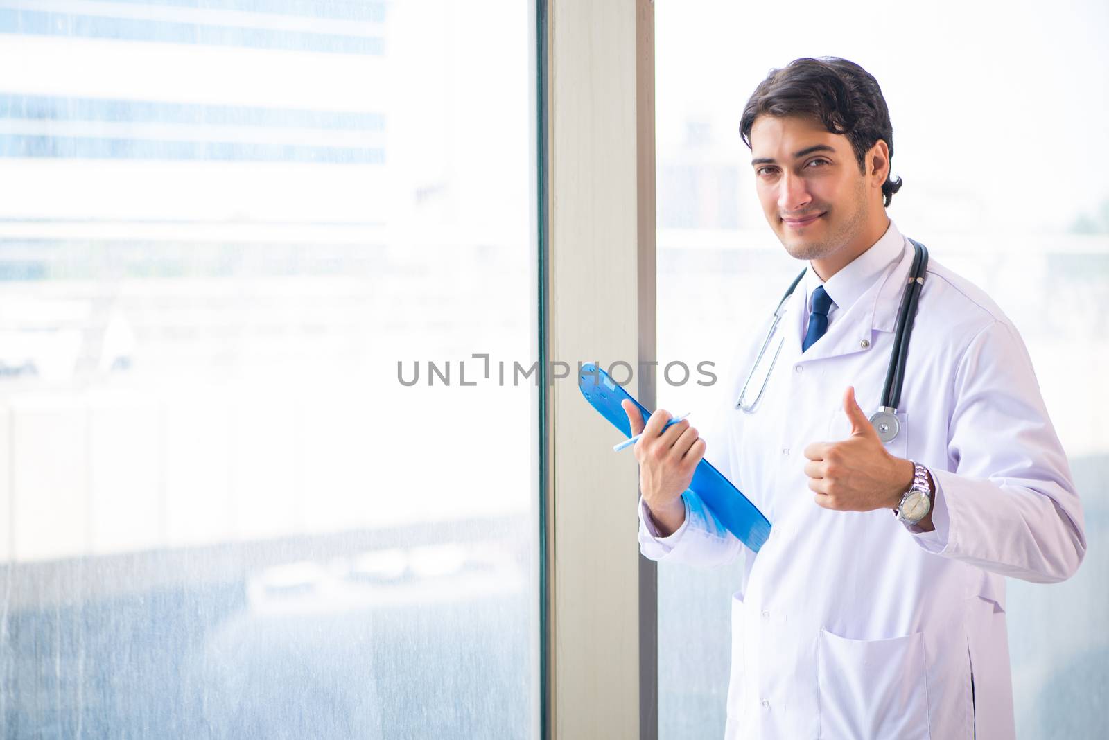 Young handsome doctor standing at the window 