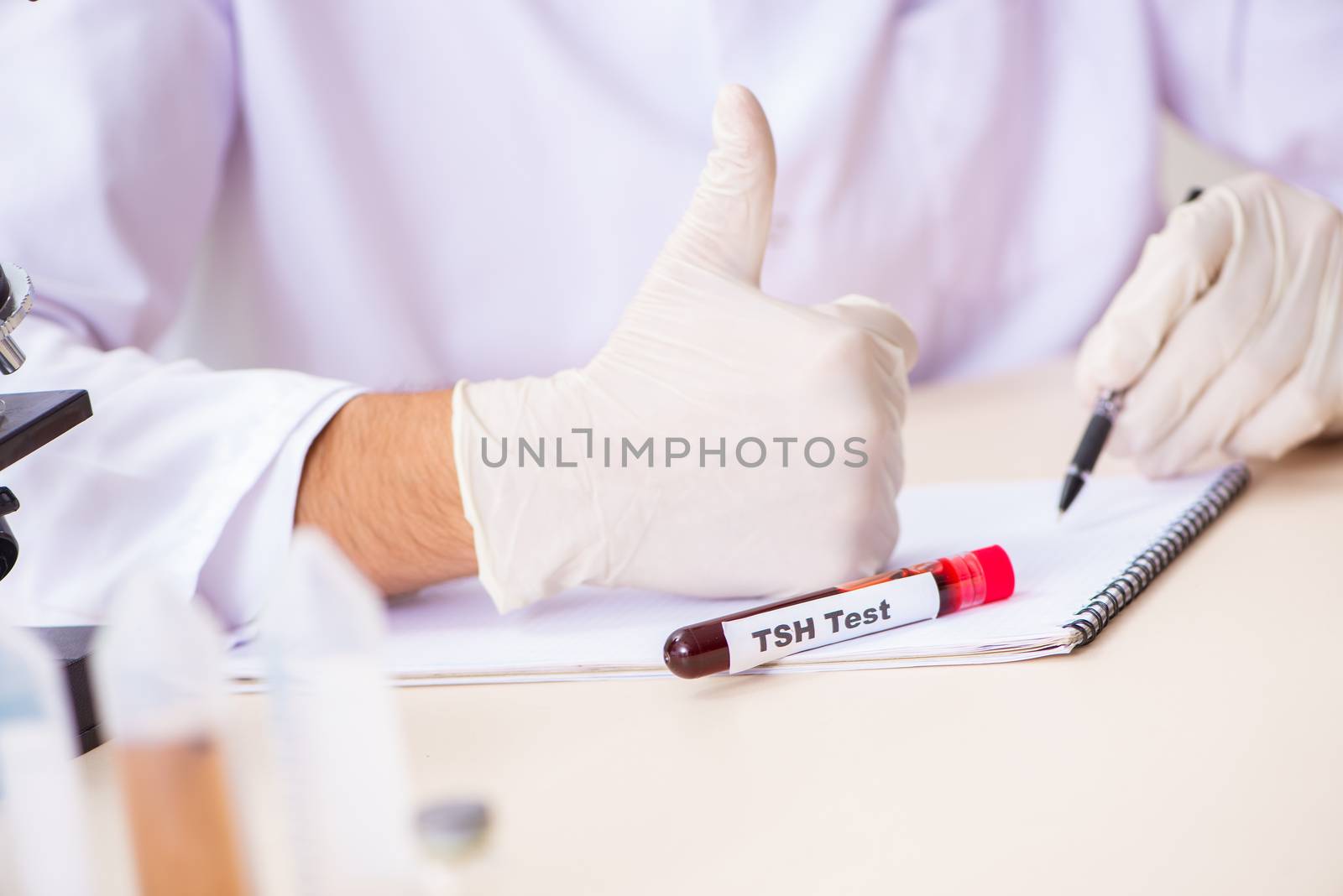 Young handsome lab assistant testing blood samples in hospital 