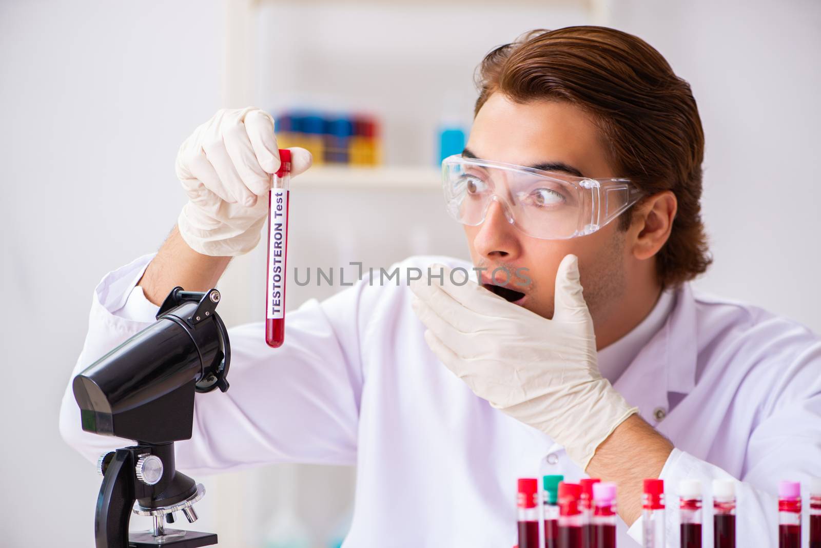 Young handsome lab assistant testing blood samples in hospital  by Elnur