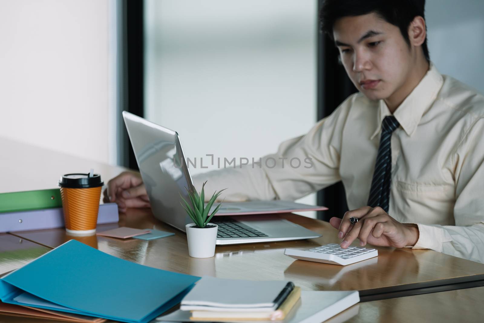 Businessman or accountant working on calculator to calculate business data, accountancy document and laptop computer at office, business concept.