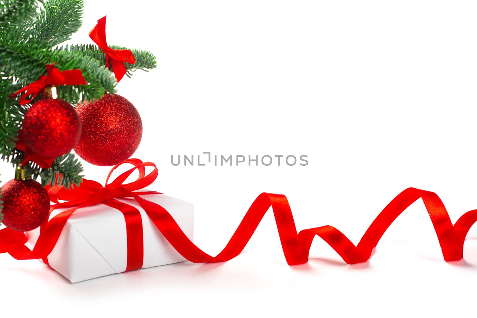 White holiday present gift box with red satin bow and curly ribbon under Christmas tree with baubles, border frame design isolated on white background