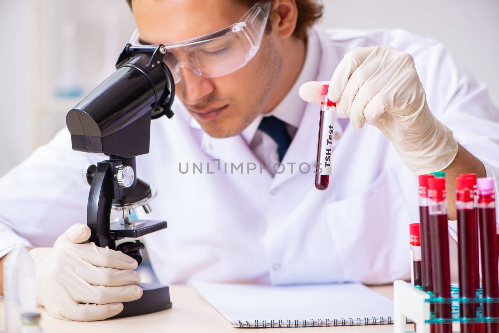 Young handsome lab assistant testing blood samples in hospital 