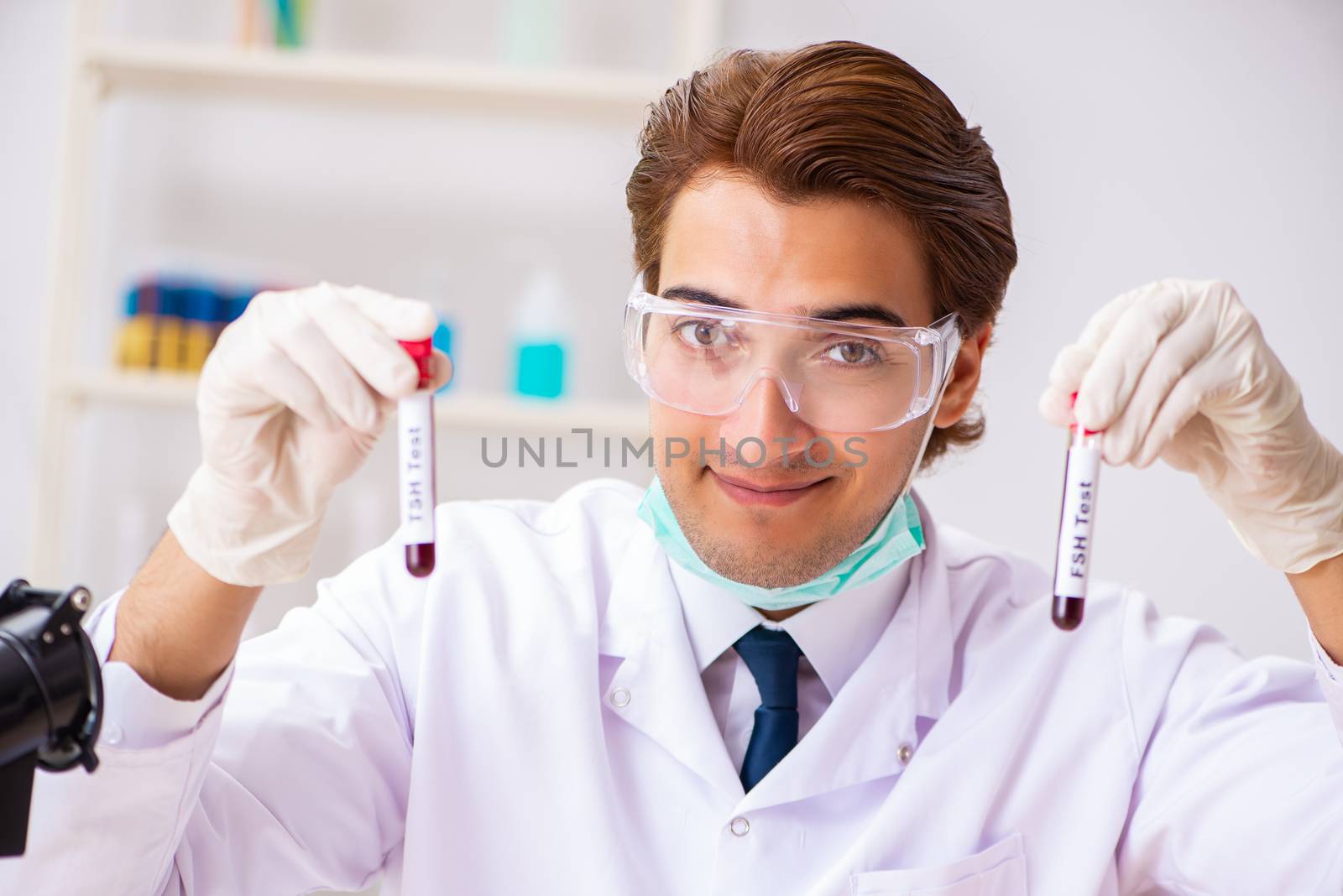 Young handsome lab assistant testing blood samples in hospital 