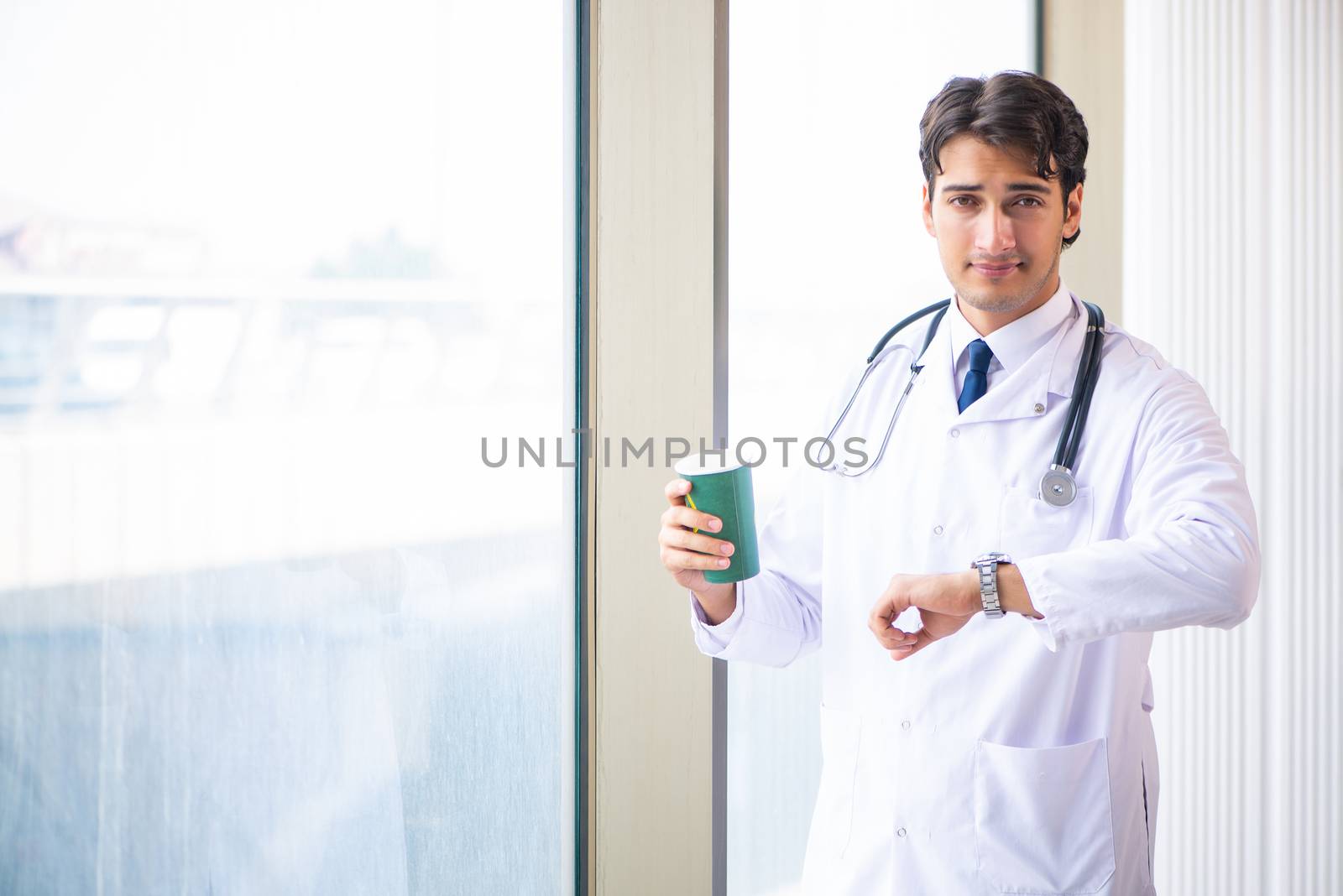 Young handsome doctor standing at the window  by Elnur