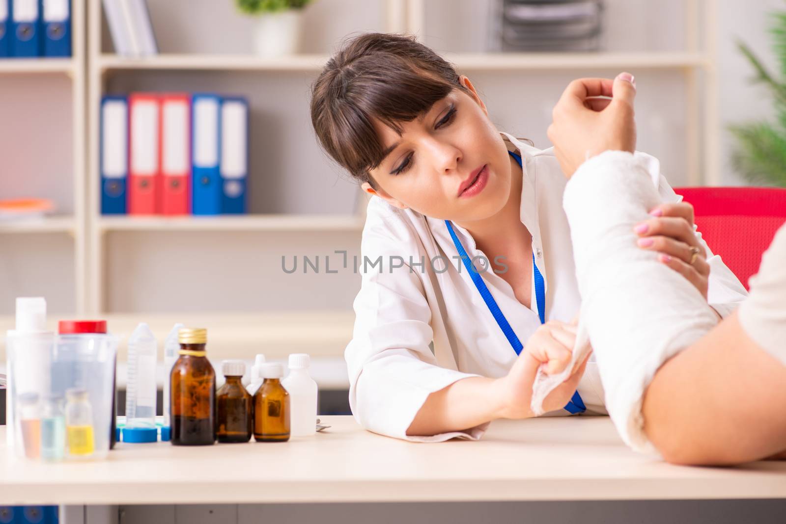 Young man with bandaged arm visiting female doctor traumatologist