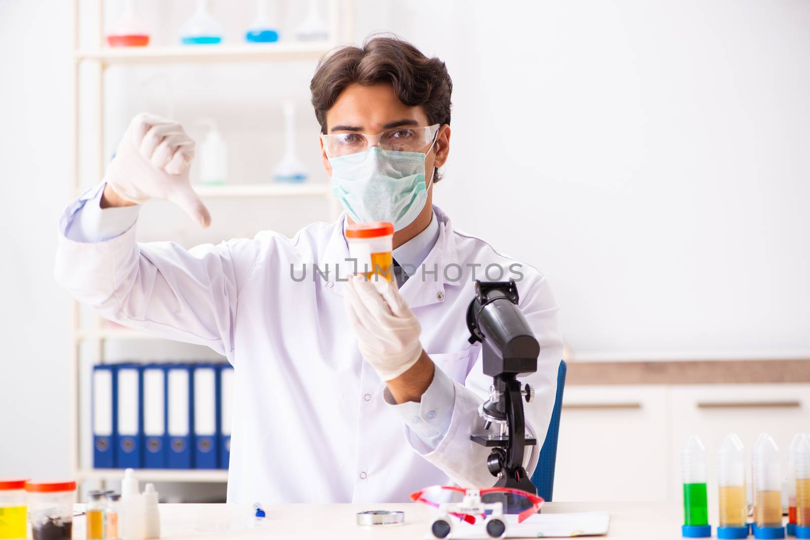 Young handsome chemist working in the lab by Elnur