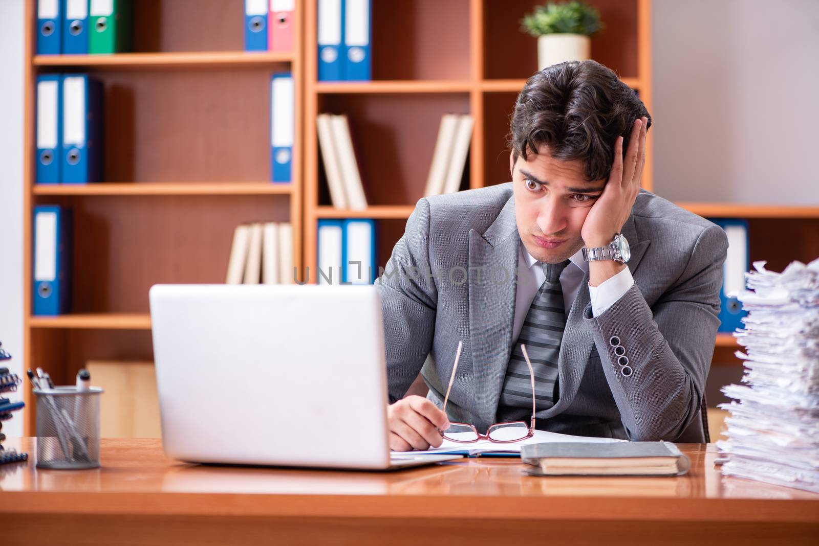 Young handsome businessman unhappy with excessive work 