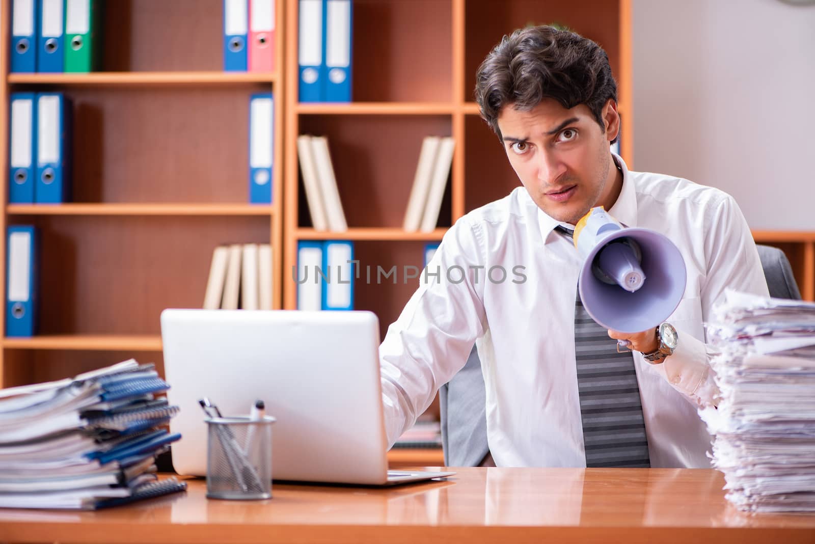 Young handsome businessman unhappy with excessive work 