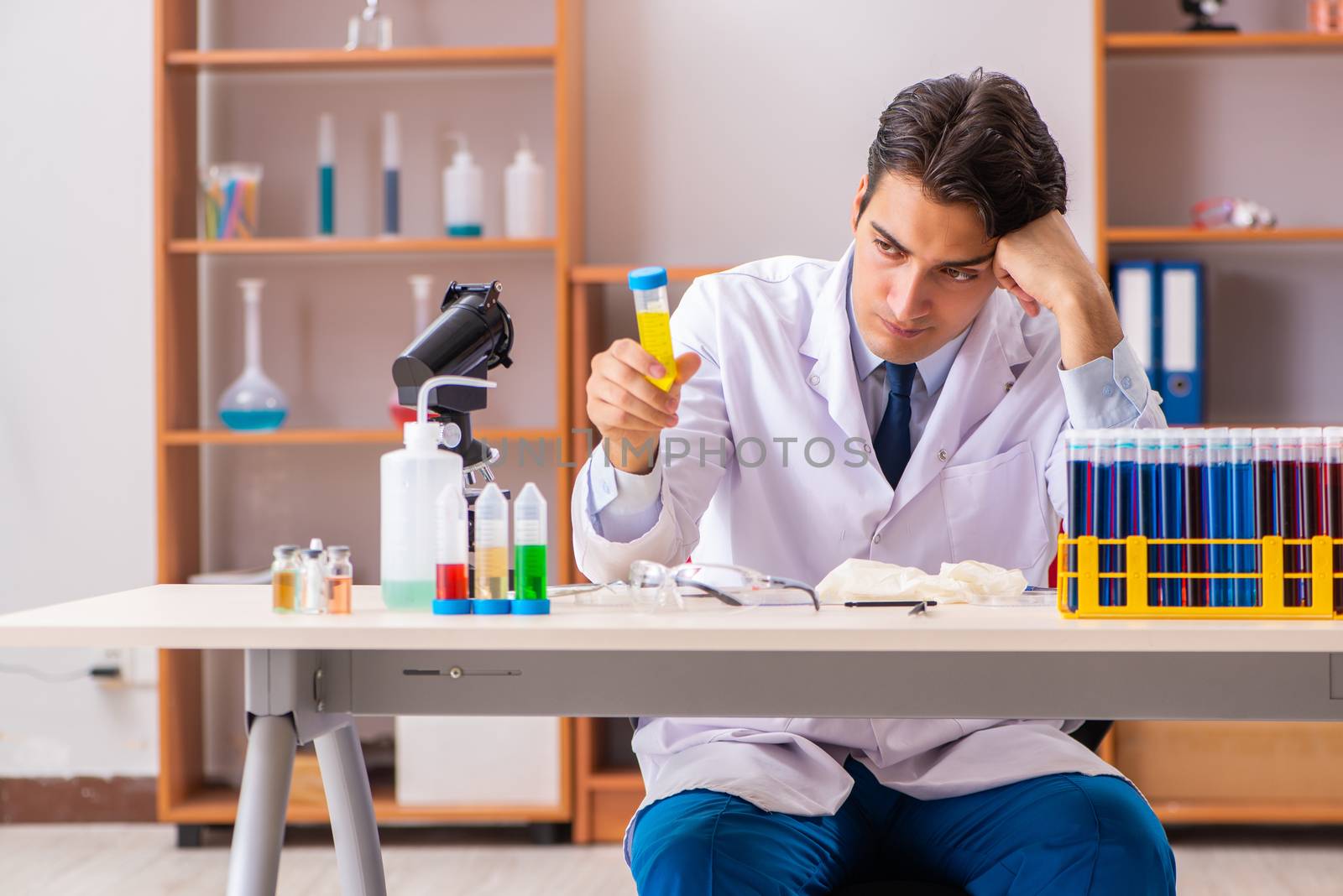 Young handsome biochemist working in the lab  by Elnur