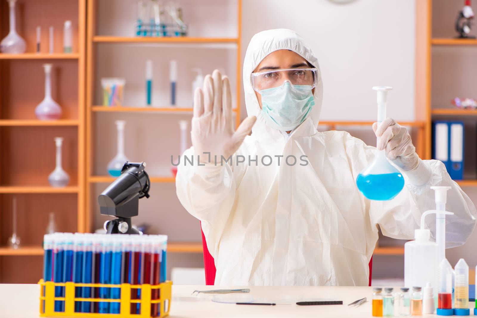 Young biochemist wearing protective suit working in the lab by Elnur