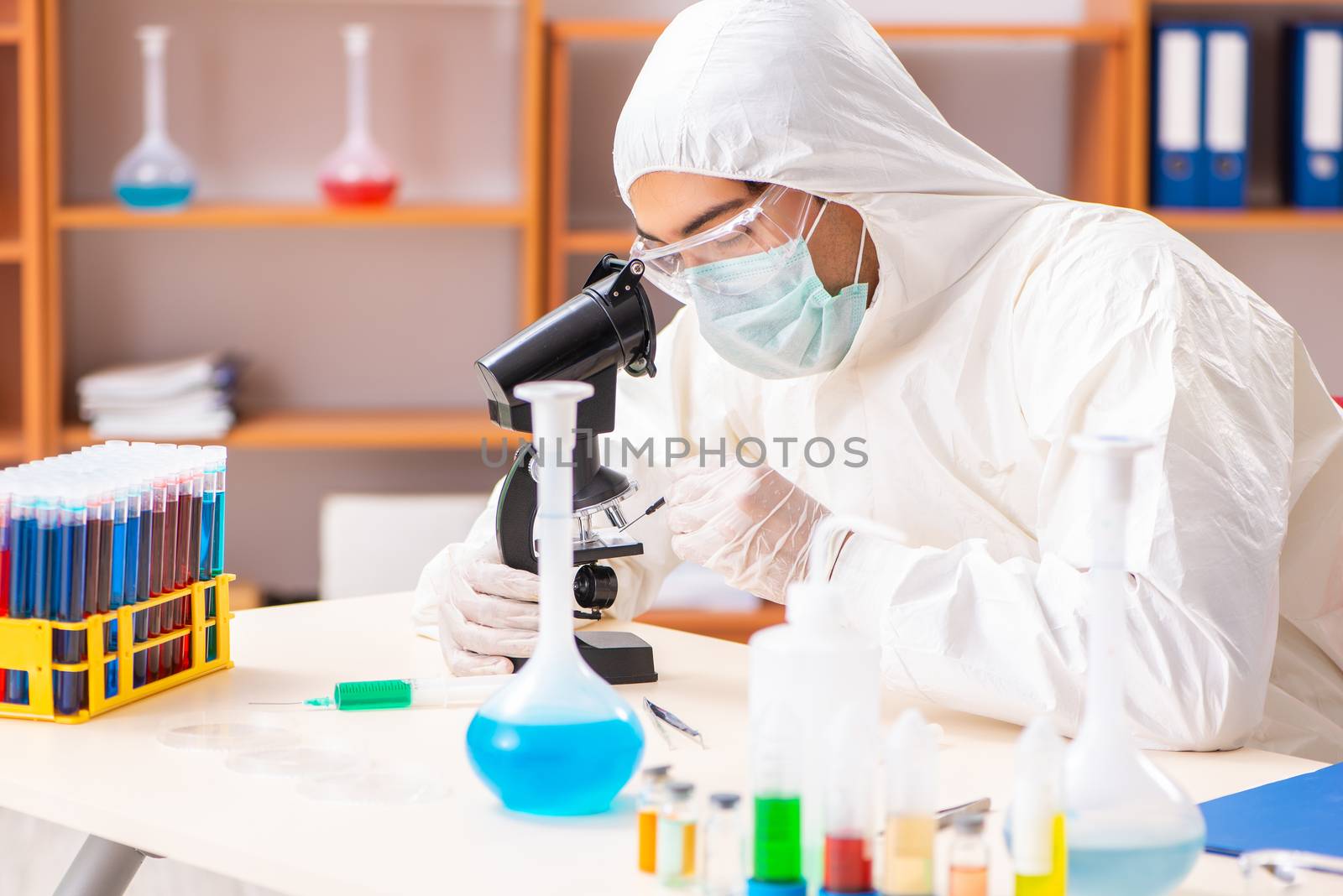Young biochemist wearing protective suit working in the lab by Elnur