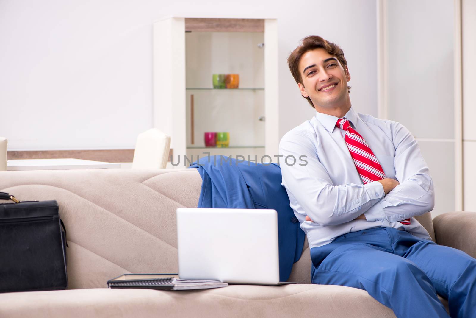 Young businessman working at home sitting on the sofa  by Elnur