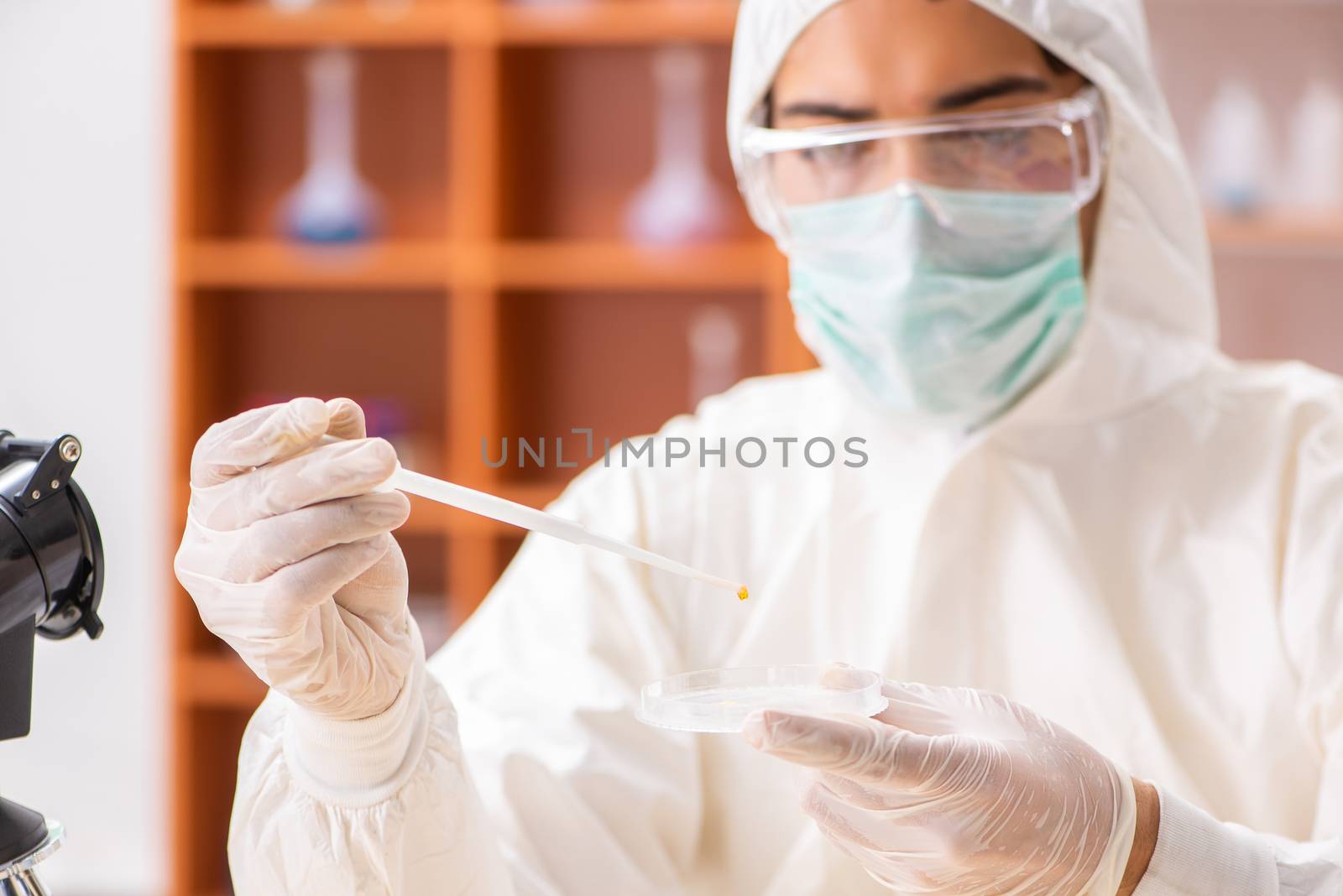 Young biochemist wearing protective suit working in the lab by Elnur