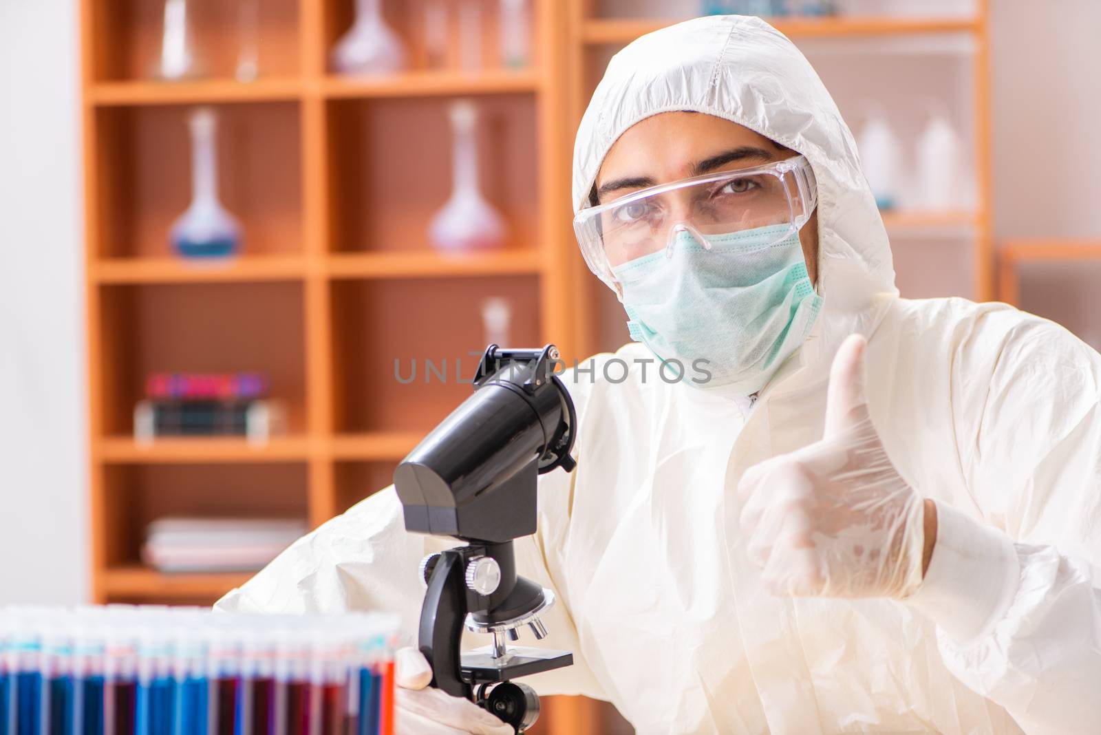 Young biochemist wearing protective suit working in the lab by Elnur