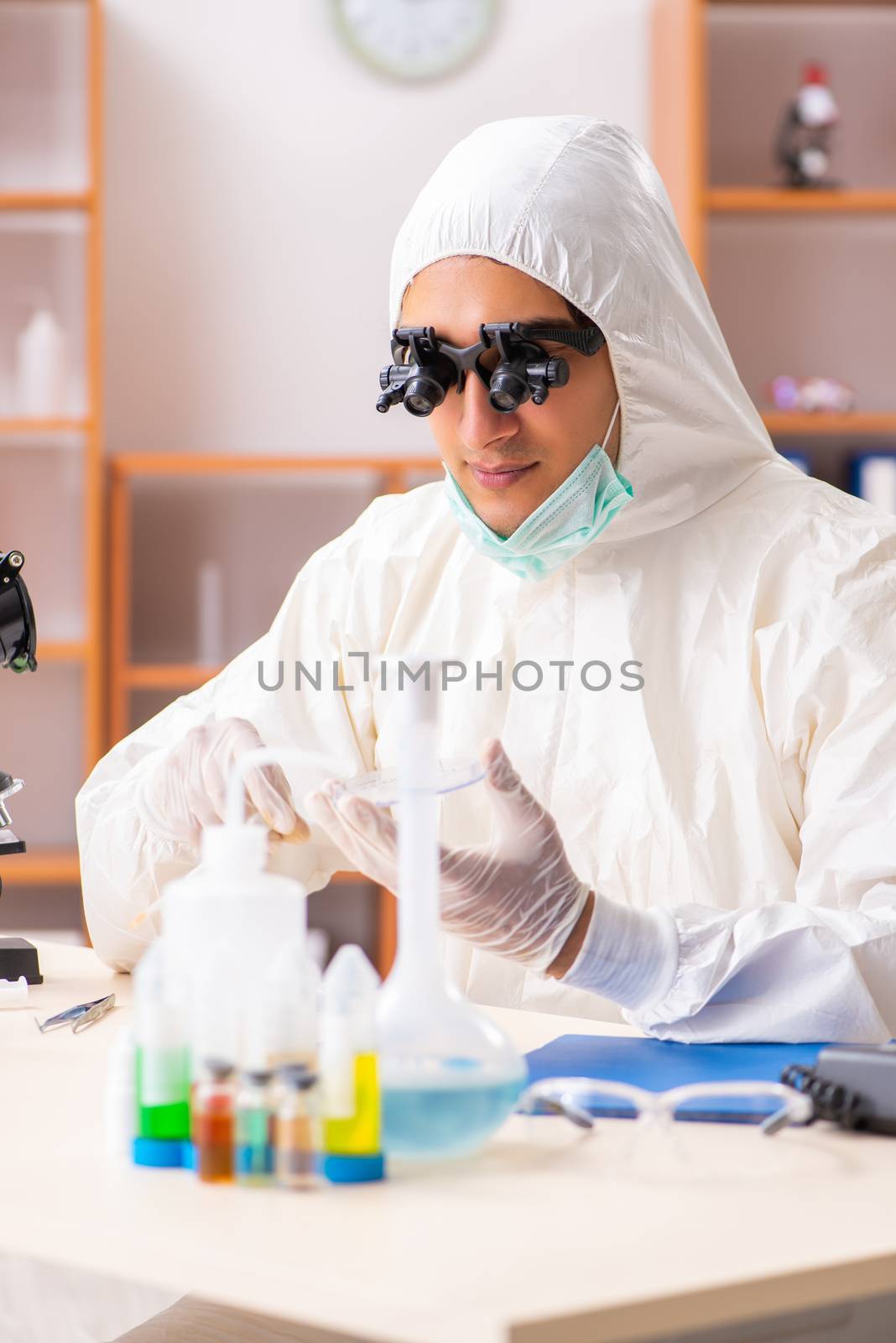 Young biochemist wearing protective suit working in the lab by Elnur