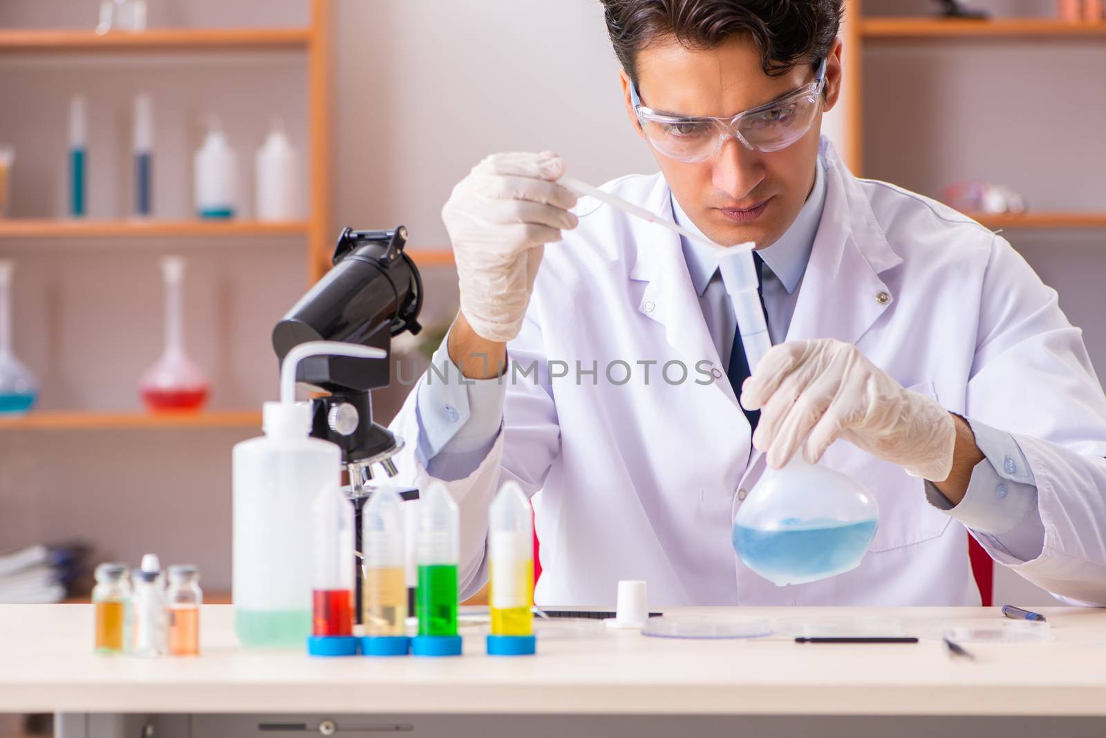 Young handsome biochemist working in the lab  by Elnur