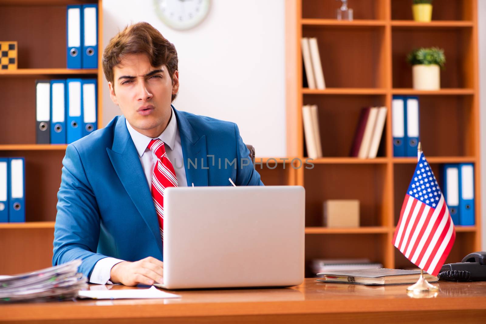 Young handsome politician sitting in office 