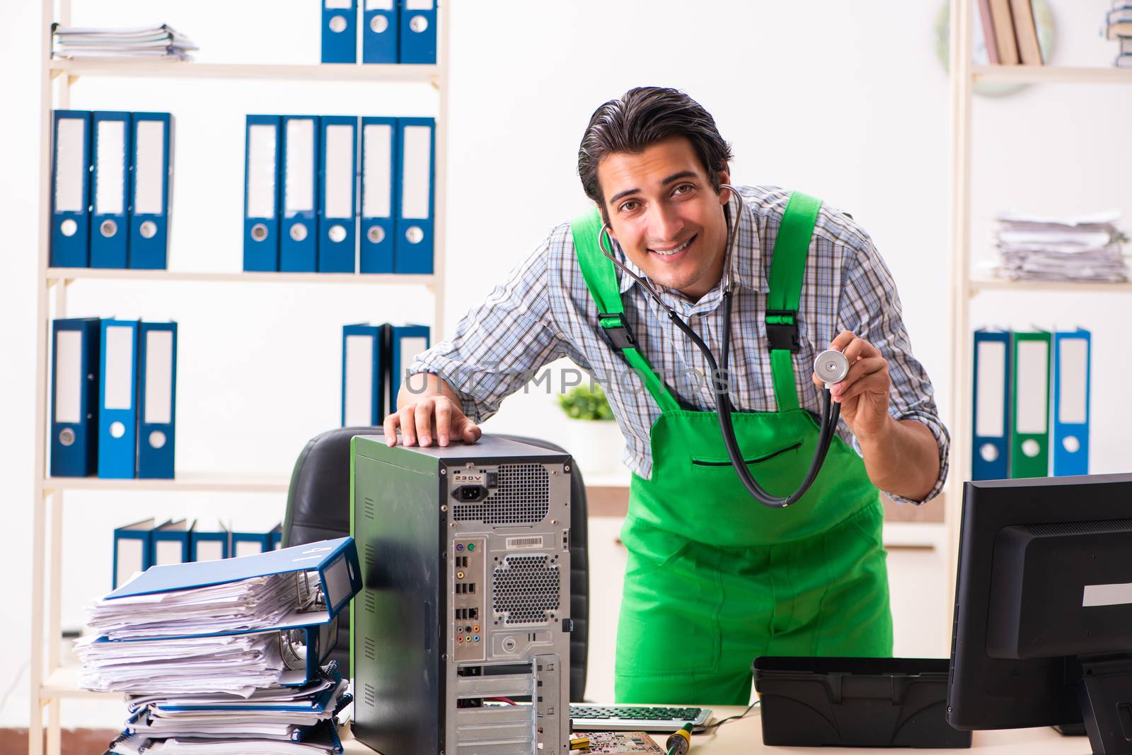 Young engineer repairing broken computer at the office  by Elnur