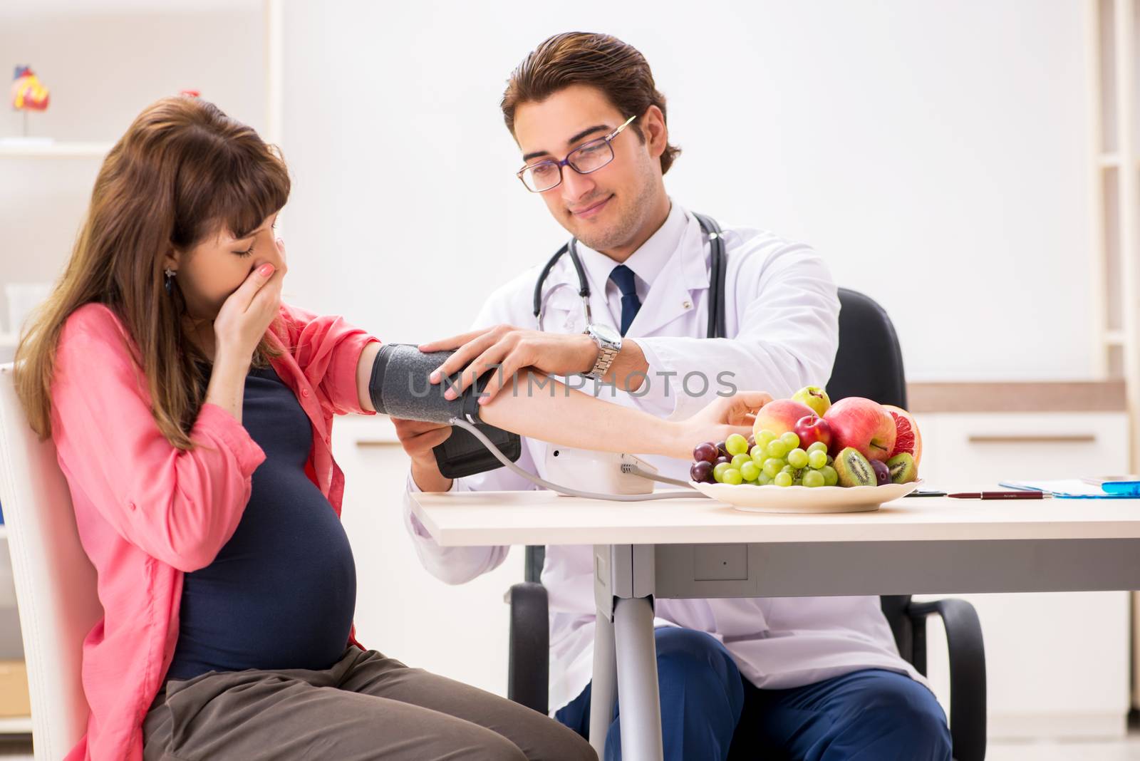 Pregnant woman visiting doctor discussing healthy diet