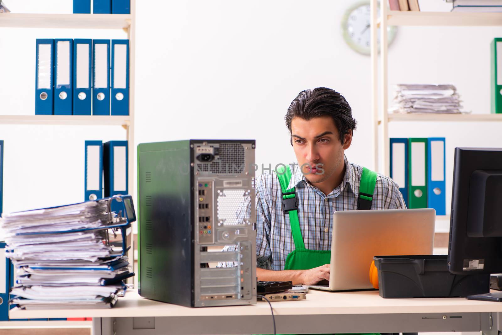 Young engineer repairing broken computer at the office  by Elnur