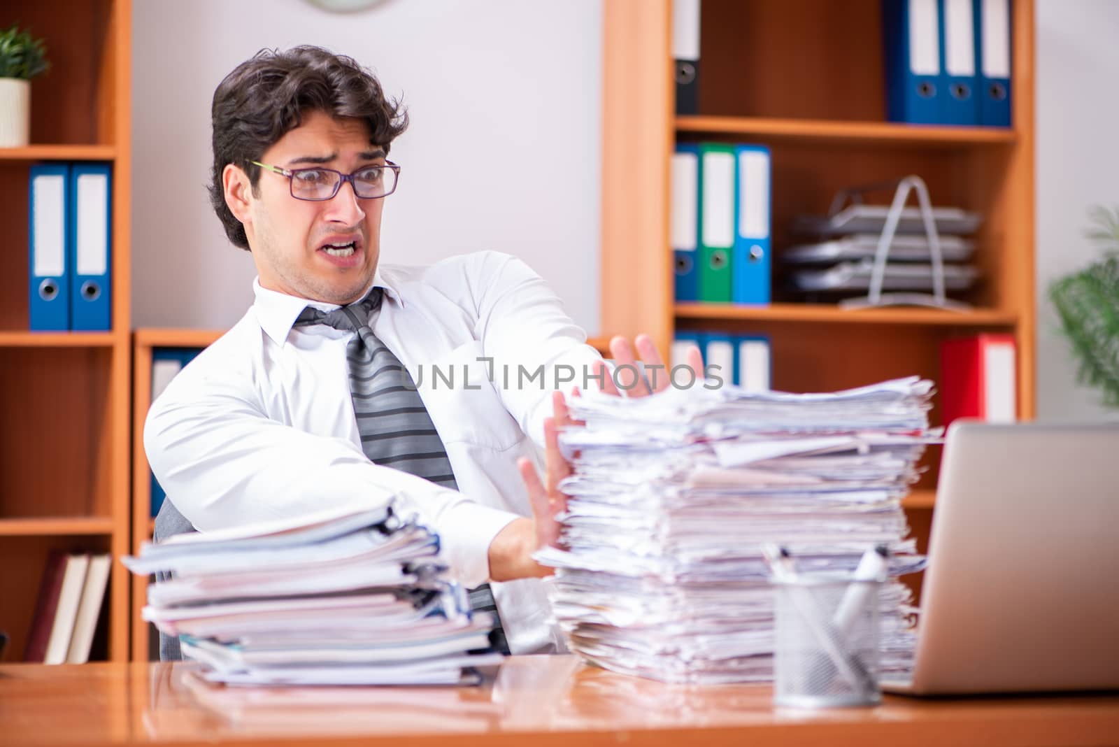 Young handsome businessman unhappy with excessive work 