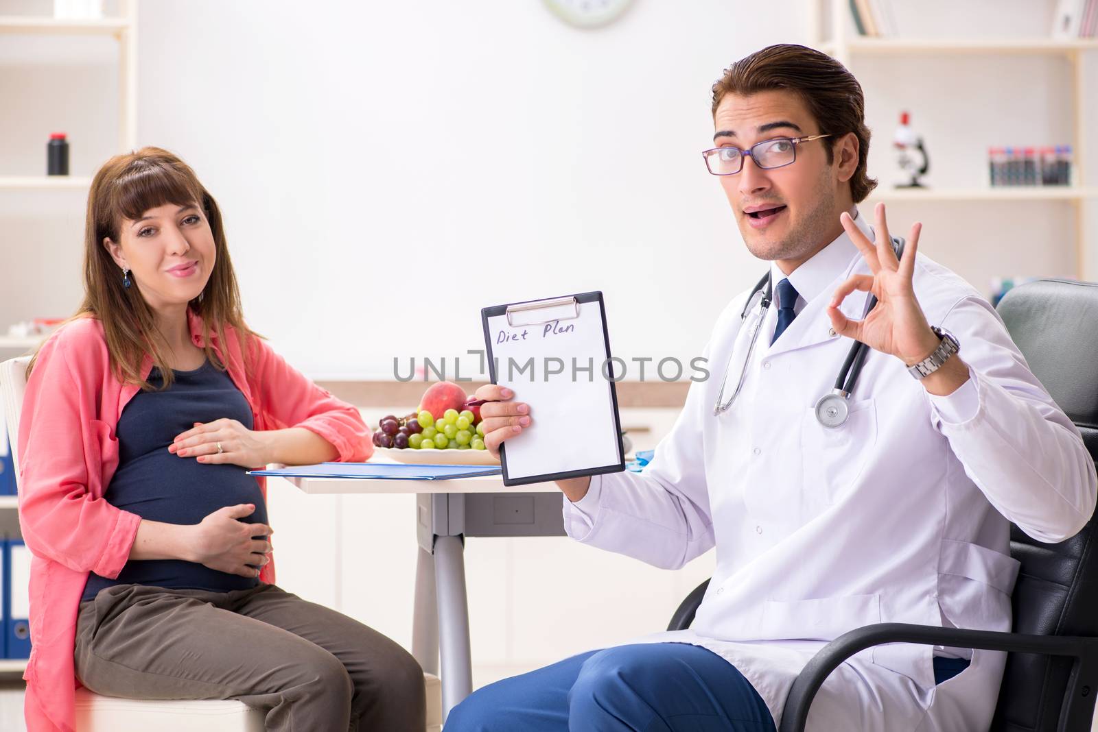Pregnant woman visiting doctor discussing healthy diet by Elnur