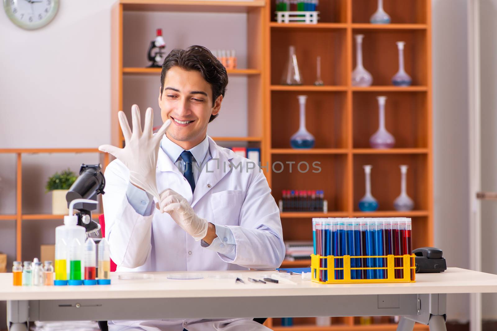 Young handsome biochemist working in the lab  by Elnur