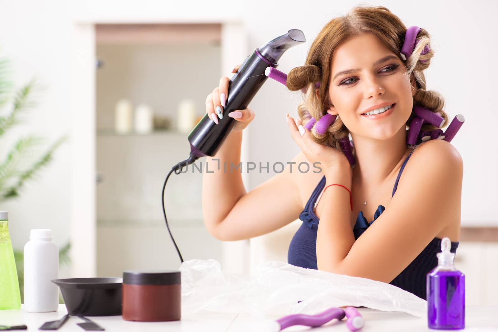 Young woman with hair curlers at barbershop 