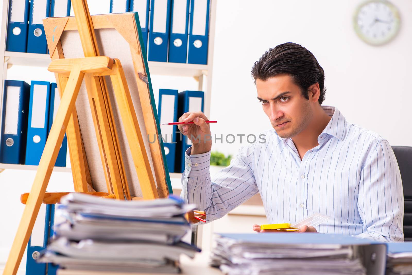 Young handsome employee enjoying painting at the office  by Elnur