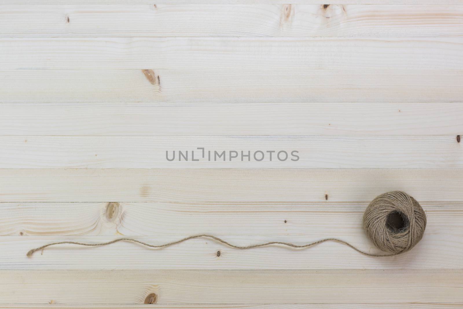Hemp rope roll placed on a pine floor background.