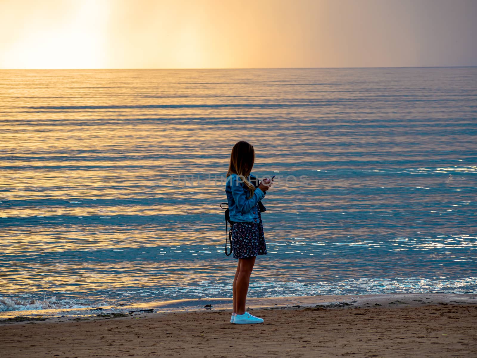 beautiful alone girl on the beach. Girl looking at stormy sea amd taking a picture with smarphone. The spectacular Storm with rain Is Coming in Estonia. Baltic sea