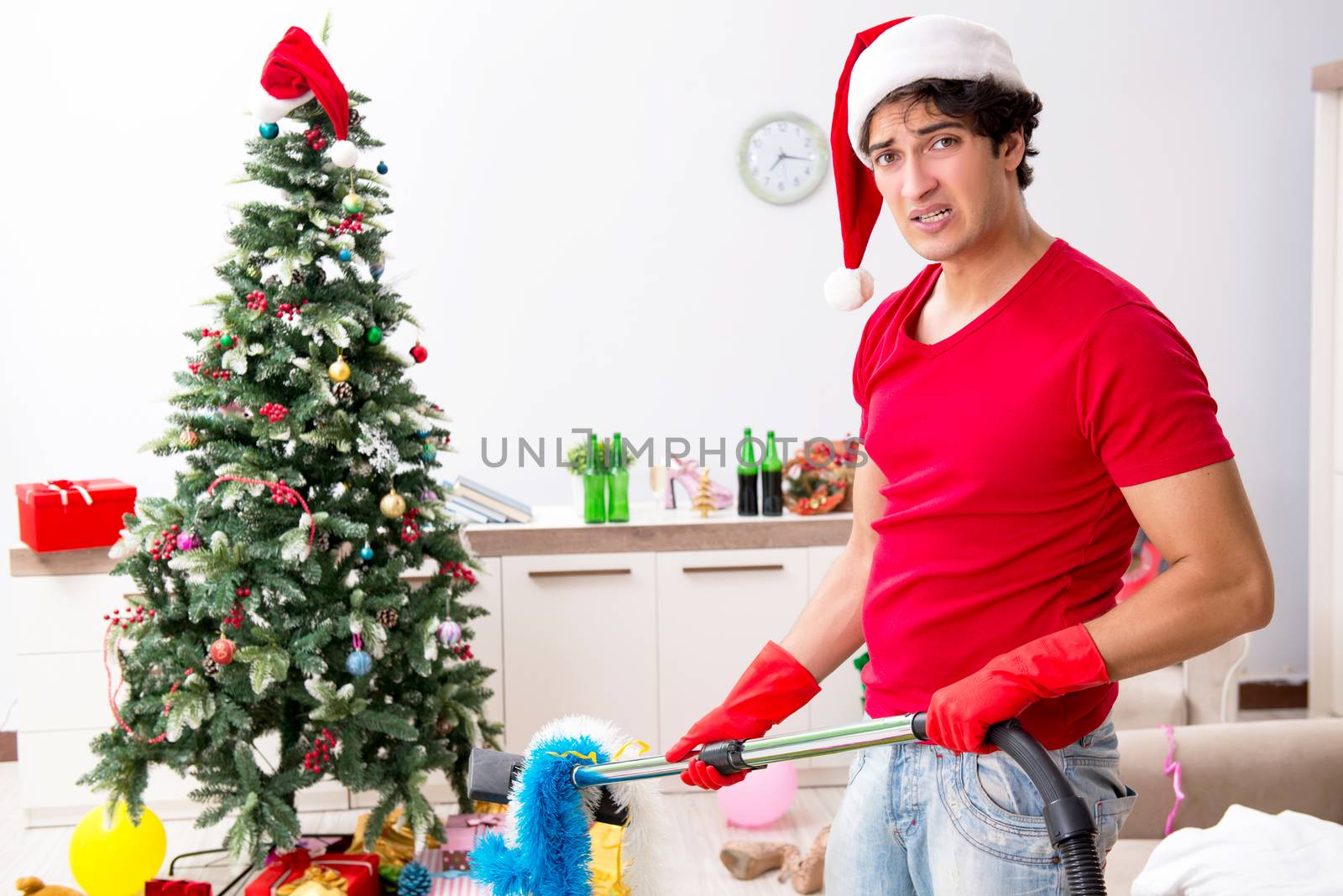 Man cleaning his apartment after christmas party by Elnur