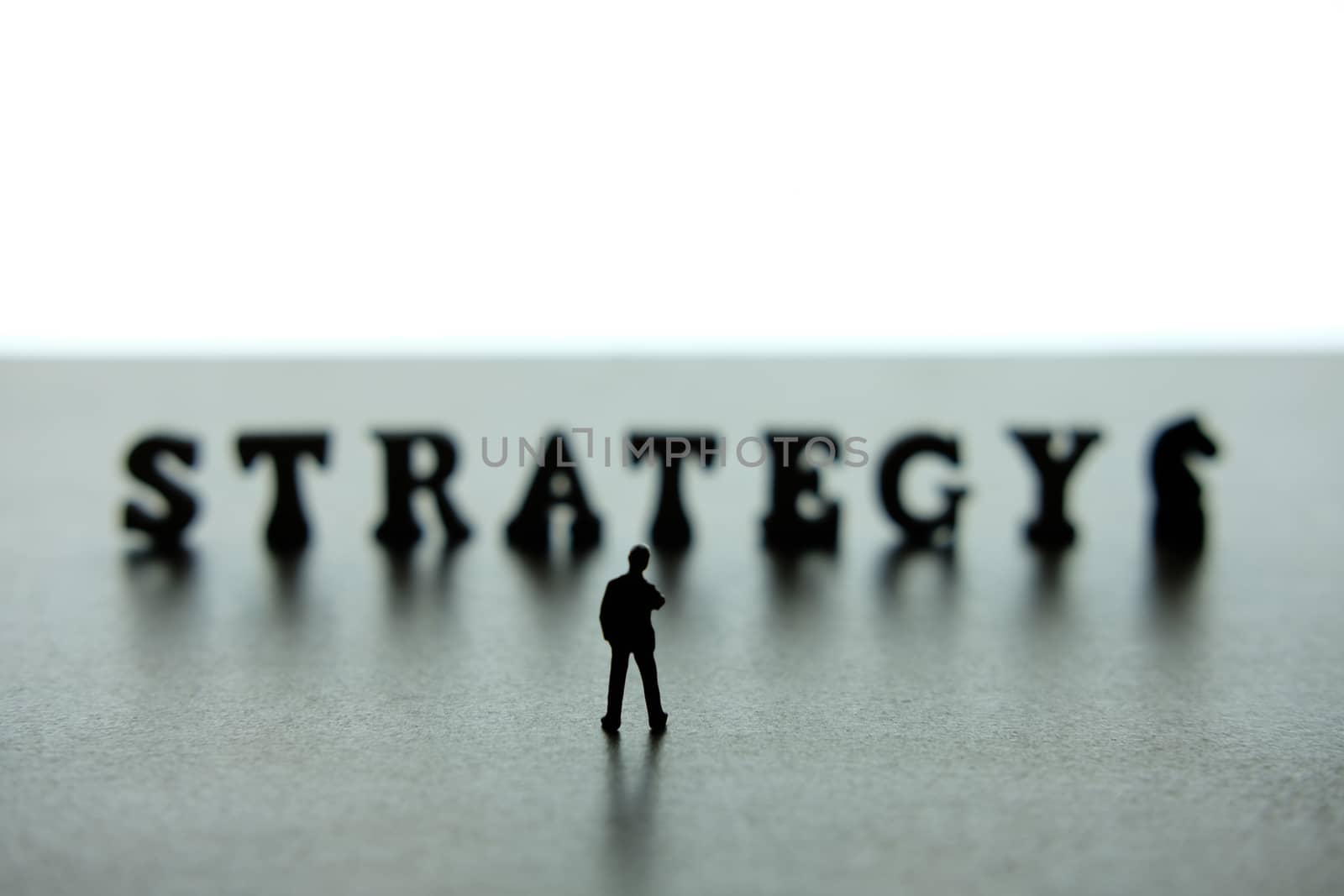 Silhouette of miniature businessmen standing and thinking in front of strategy word block puzzle. image photo