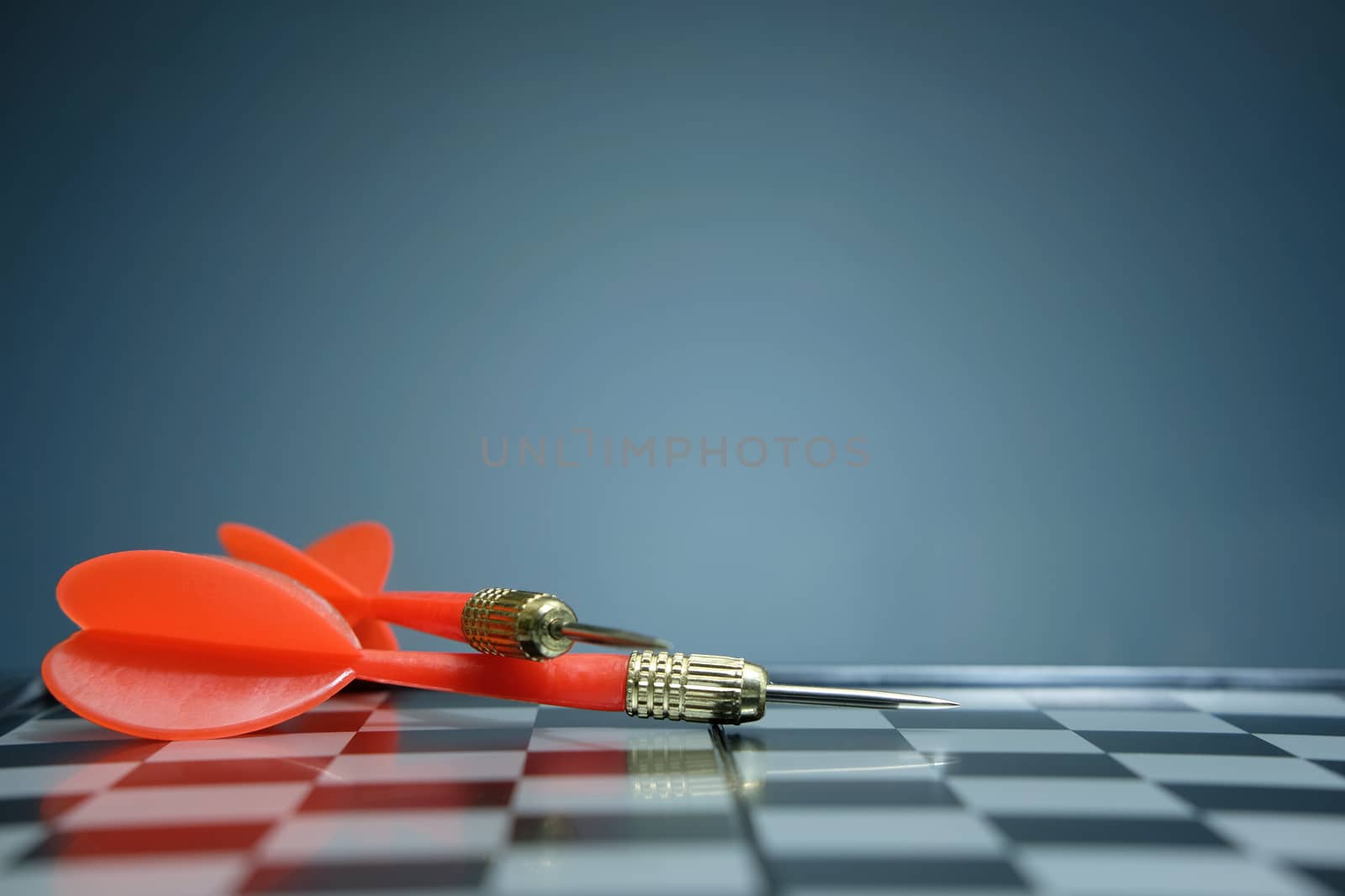 Red dart arrow laying on chess board with dark grey background. Image photo