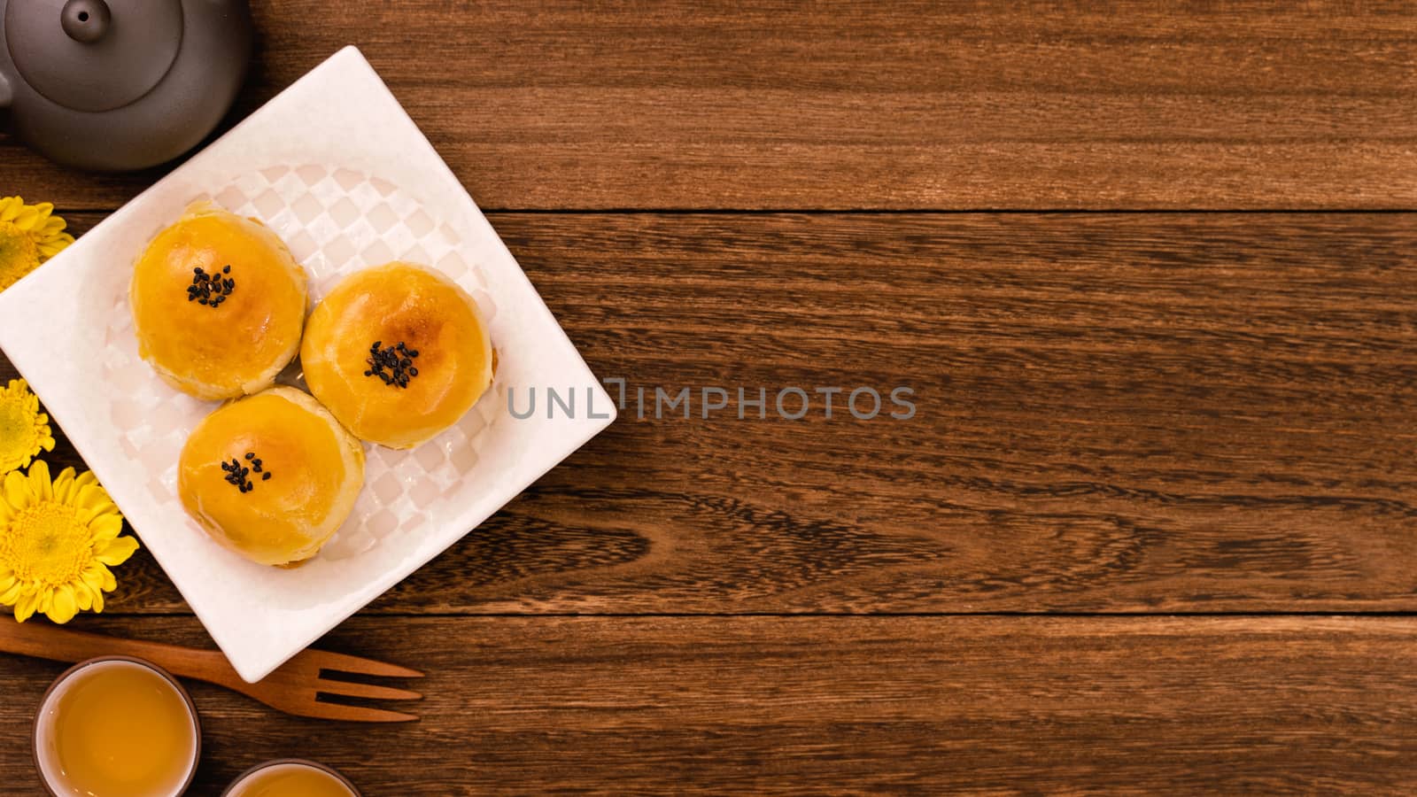 Moon cake for Mid-Autumn Festival, delicious beautiful fresh mooncake on a plate over dark wooden background table, top view, flat lay layout design concept.
